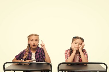 Alternatif eğitim fikri. Sevimli çocuklar beyaz izole masalarda oturuyor. İlköğretim okulunda öğrenen küçük kızlar. Küçük çocuklar örgün eğitim alıyor. Zorunlu eğitim ücretsizdir