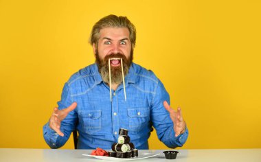 Çubuklu suşi ve zencefil. Japon mutfağı. Japonya 'da geleneksel yiyecekler. Şef yemek servisi. Asya yemeği. Suşi siparişi. Sushi teslimatı. Mutlu adam suşi yer.