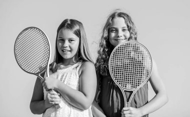 Dinlenme zamanı. Sportif bir oyun. Açık hava oyunları. Tenis oyna. çocukluk mutluluğu ve kardeşlik. Tenis raketli küçük kızlar. Yaz sporları aktivitesi. Enerjik çocuklar. Mutlu ve neşeli.