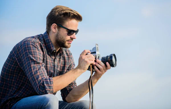 Blogger skjuter vlog. Snygg bloggare resenär retrokamera. Manuella inställningar. Fotojournalistkonceptet. Resebloggare. Journalisten tar kort. Killen utomhus blå himmel bakgrund. Vintageutrustning — Stockfoto