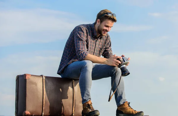 Mundo para ver. periodista con cámara. viaje de negocios. macho hombre turista sentarse en la bolsa de viaje. viajero espera el vuelo. Muévanse. sexy hombre cielo fondo. estilo de moda masculina. se ve tan de moda —  Fotos de Stock