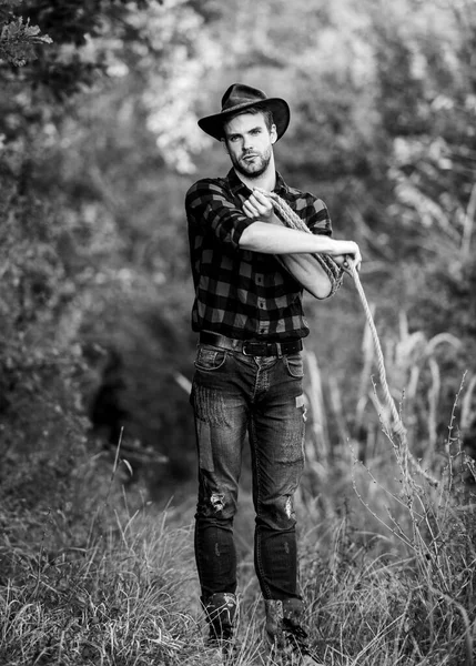 Attle breeding concept. Cowboy at countryside. Ranch occupations. Man cowboy nature background. Man wearing hat hold rope. Ranch owner. Lasso tool. American cowboy. Lasso tied wrapped. Western life — Stock Photo, Image
