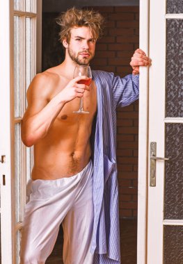 Yatak odası kapıdan çıkan seksi çekici maço tousled saç. Seksi gövdeli adam şarap içer. Seksi sevgili kavramı. Adam pürüzsüz cilt bornoz giymek. Harika bir akşamın başlangıcı. Bachelor seksi vücut