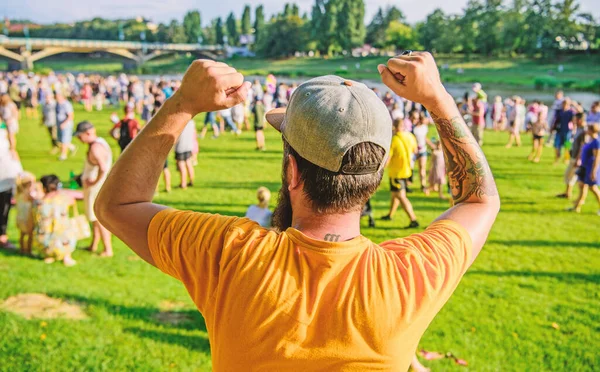 Guy celebrate holiday or festival. Summer fest. Man bearded hipster in front of crowd. Open air concert. Book ticket now. Early bird sale. Music festival. Entertainment concept. Visit summer festival