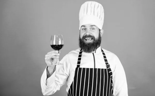 Вітаю друзів. Алкогольний напій. Червоне вино в склянці. Професійний шеф-кухар у формі кухаря. Це вино просто ідеальне. Впевнений чоловік сомельє вивчає келих з вином. Щасливий бородатий чоловік — стокове фото
