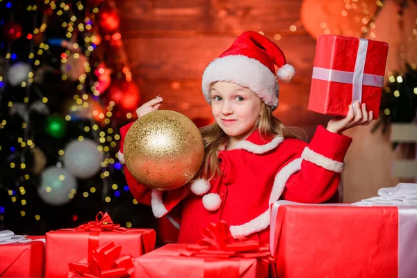 O Pai Natal trouxe-me presentes. Felicidade e alegria. Criança menina feliz animado encontrar presentes perto da árvore de Natal. Feliz Natal! Feliz Natal! Feliz conceito de infância. Kid wear Santa hat hold embrulhado caixa de presente de Natal — Fotografia de Stock