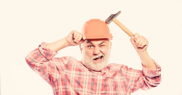 Чоловік бородатий працівник носить шолом, тримаючи молоток. Ремонтна майстерня. Концепція ремонту. Старший працівник виконкому. Ремонт домашнього майстра. Досвідчений інженер. Ремонт або реконструкція. Ремонт будинку — стокове фото