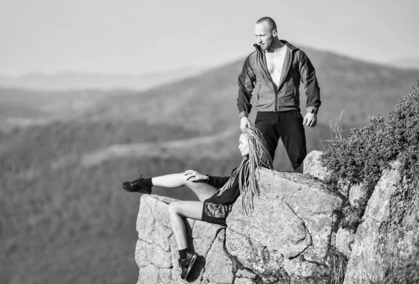 世界の端に女性は崖の高い山の風景の背景の端に座ります。カップルのハイカーは眺めを楽しま。穏やかな瞬間をハイキング。観光客のハイカーの女の子と男がリラックス。ハイキングの特典。ハイキングの週末 — ストック写真