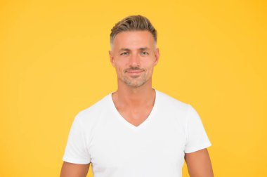 Yakışıklı adam. Adam sarı arka plan. Sakallı ve saç tıraşlı traşsız bir adam. Erkekler tımar ediliyor. Berber dükkanı. Sıradan tarzda yakışıklı bir adam. Moda ve tarz