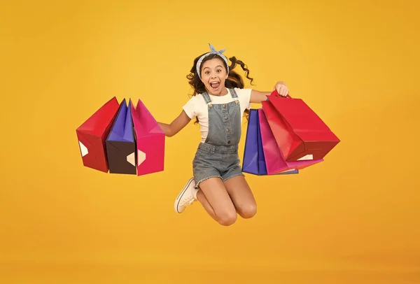 Acele et. Toptan satış. Çocuk modası. Satış ve indirimler. Başarılı bir alışveriş yaptıktan sonra mutlu küçük kız. Ağır çantalarla enerjik çocuk atlayışı. Paketlerde bayram hediyeleri. Siber pazartesi. Alışveriş zamanı. — Stok fotoğraf