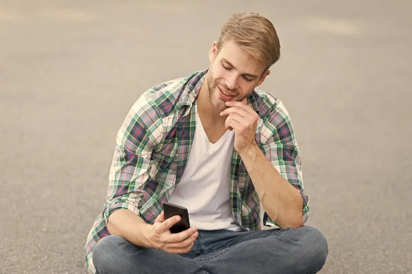 Estudiante despreocupado. tiempo libre. moda de verano. Hombre guapo camisa a cuadros. moda masculina. estudiante relajarse. ver videollamada por teléfono. macho chico charlando al aire libre. Estilo callejero. hombre sentarse en el suelo — Foto de Stock