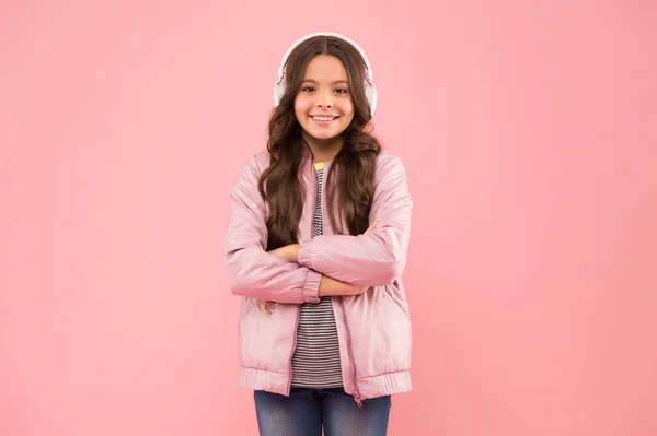 Colegiala sonriente. Disfrutando de la canción tocando en los auriculares. Fiesta de karaoke divertida. Diversión y entretenimiento. Unirme a una canción. Niña con aspecto triste fondo rosa. Pequeño niño escuchar sonido estéreo —  Fotos de Stock