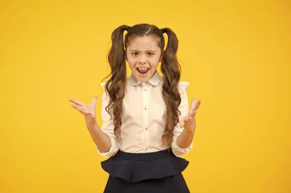 Opnieuw mislukt. Woedend schoolmeisje. Kleine schoolmeisje gebaren haar vuisten met woede op gele achtergrond. Klein schoolmeisje schreeuwen van stress of falen. Schoolmeisje heeft problemen op school — Stockfoto