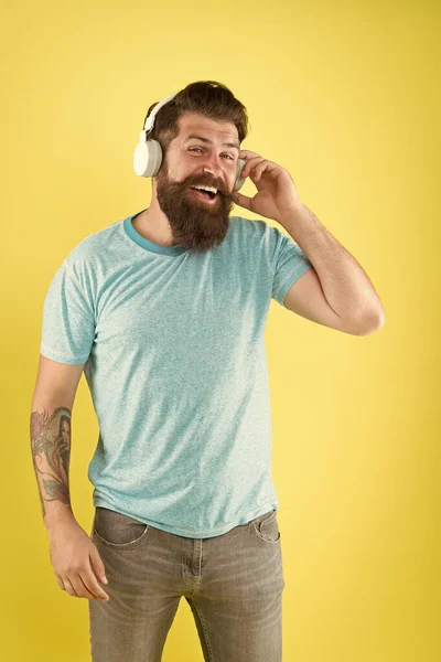 Freedom going wireless offers you is unparalleled. Wireless headphones designed to deliver clean sound. Bearded man listening music wireless gadget. Hipster happy using modern wireless headphones — Stock Photo, Image