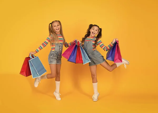 Ωραία αγορά. Αγοραστής έννοια του καταναλωτή. Εξοικονόμηση διακοπών. Μικρά παιδιά βαριές τσάντες για ψώνια. μεγάλη πώληση δώρων. Χαρούμενα παιδιά. Τα μικρά κορίτσια νοιάζονται για τα πακέτα. Ελεύθερη πτώση. Καλοκαιρινά ψώνια — Φωτογραφία Αρχείου