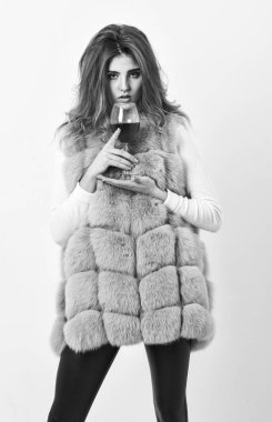 Kız makyajı kürk manto giyer, şarap kadehi tutar. Kadın model kıvırcık saç modeli pahalı lüks şarabı seviyor. Hedonizm konsepti. Kışın kırmızı şarap içmek için sebepler. Kadın şarap içiyor.