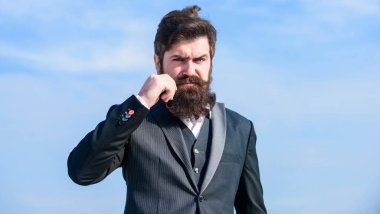 Sakallı hippi adam resmi takım elbise giyer mavi gökyüzü arka planı. Klasik sakal. Sakal ve bıyık bakımı. Sakal modası modası. Tımar rutiniyle başla ve daha iyi bir dünya kur.