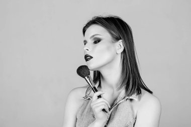 İyi görünüyorsun ve kendine güveniyorsun. Makyaj fırçası kullanan çekici bir kadın. Profesyonel makyaj malzemeleri. Makyöz konsepti. Kadınlığı vurgula. Kız göz farı takıyor. Cilt bakımı kozmetikleri