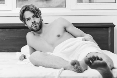 Genç adam sabahları uyanırken geriniyor. Genç adamın yatakta gerindiğini gösteren bir resim. Gülümseyen, rahatlatan güneş ışığı.