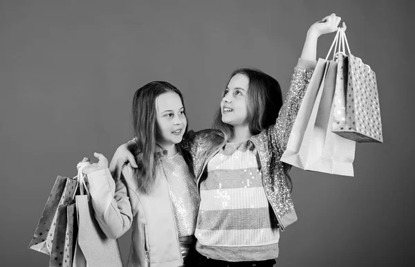 Moda infantil. assistente de loja com pacote. Vendas e descontos. Irmandade e família. poupança em compras. Meninas pequenas com sacos de compras. Filhos felizes. Pequena menina irmãs compras online — Fotografia de Stock