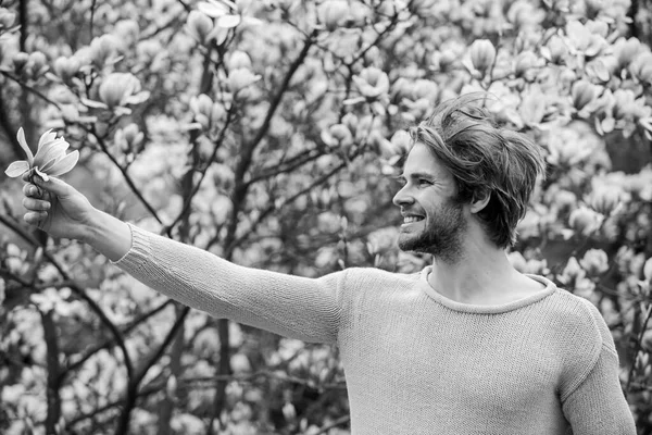 Conceito de cosméticos florais. Hipster desfrutar de aroma de flor. Penteado estilo. Homem flores fundo desfocado. Bela primavera. Natureza botânica. Beleza masculina. Cuidado com o cabelo e beleza. Homem não barbeado magnólia flor — Fotografia de Stock