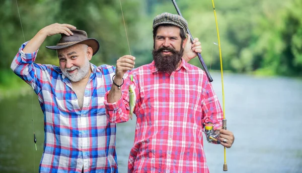 在休息的时候。男人的友谊家庭联系。父亲和儿子钓鱼。两个快乐的渔夫拿着钓竿。夏天的周末成熟的渔夫。业余爱好和体育活动。鳟鱼饵 — 图库照片