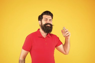 Losyon ve sprey. Parfüm ürünleri konsepti. Sakallı, yakışıklı adam şişe parfümü kullanıyor. Parfüm sürmüş. Erkeklere göre parfüm seç. Gün boyunca taze kokmasını sağla.