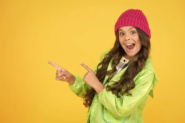 Elige entre lo más lindo y lo más de moda. Chica pelo largo fondo amarillo. Concepto de temporada fría. Accesorio de moda de invierno. Niño pequeño con sombrero caliente. Niña usar sombrero de punto. Accesorio sombrero de invierno — Foto de Stock