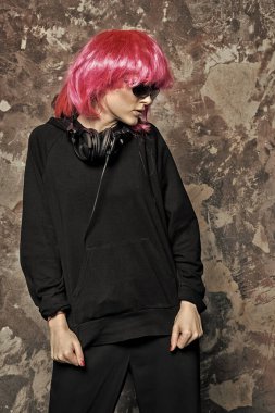 Güneş gözlüklü kız, soyut duvarda kulaklık, klasik filtre.