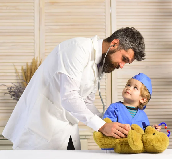 Il veterinario e il piccolo assistente esaminano l'orsacchiotto. Padre e figlio — Foto Stock