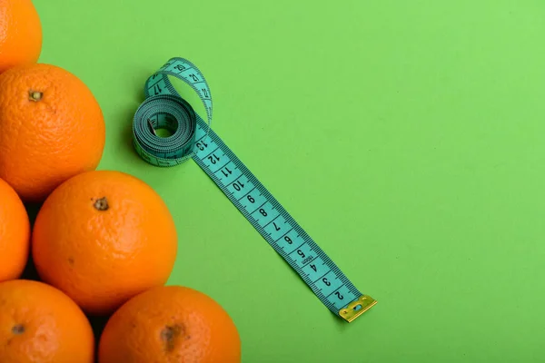 Oranges près de long ruban à mesurer sur fond vert, vue de dessus — Photo