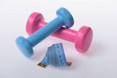 Beyaz zemin üzerinde mavi ve pembe plastikten yapılmış dambıllar