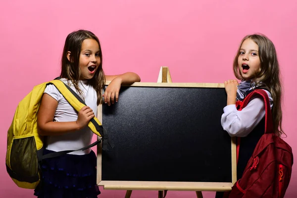 Dzieci noszące torby szkolne opierają się na błyszczącej tablicy, kopiują przestrzeń — Zdjęcie stockowe
