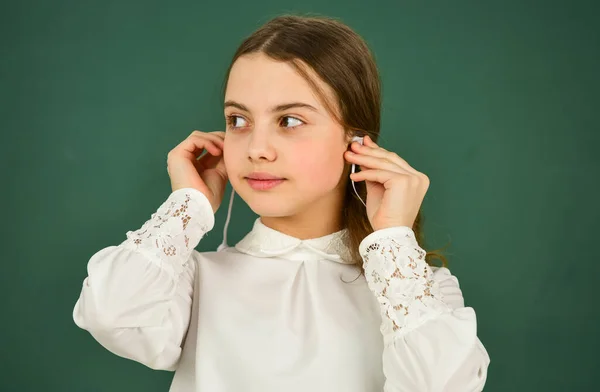Cooles Mädchen mit Kopfhörern, das Musik hört. E-Learning-Konzept. Online-Schulbildung zu Hause. zurück zur Schule. kleines Mädchen mit Kopfhörern an der Tafel. Hörbuch anhören. kostenloses eBook — Stockfoto