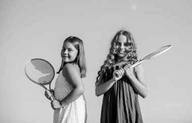 Enerjik çocuklar. Mutlu ve neşeli. Sportif bir oyun. Açık hava oyunları. Tenis oyna. çocukluk mutluluğu ve kardeşlik. Tenis raketli küçük kızlar. yaz sporları aktivitesi