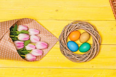 Bahar vibes. Renkli parlak yumurta ve buket taze Lale çiçek sarı arka plan üzerinde görünümü top. Bahar tatili. Gelenek Paskalya kutlamak. Mutlu Paskalya sezon. Paskalya yumurta sembolü. Paskalya geliyor