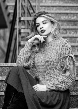 Giyilebilir trendler. Sonbahar formülü. Sonbahar için Süveter ve Etek Kombo stili. Harika saç stili olan kadın merdivenlerde dışarıda oturuyor. Sonbahar moda trendi. Kız eteğinin üzerine büyük katman örülmüş.