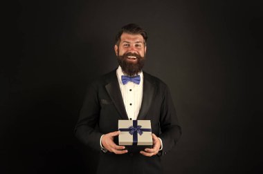 Tatili mükemmel bir hediyeyle kutlayın. Şimdiki mutlu iş adamı. Sakallı adam hediye kutusunu tutuyor. Hediye alışverişi. Hediyelik eşya dükkanı. Kutlama ve hazırlık. Hatıra olarak. Vermenin sevinci