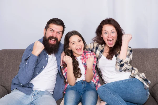 La unidad es nuestro poder. Fin de semana finalmente. Niña relajándose con los padres. Quédate en casa. La familia se sienta en el sofá. Feliz padre, madre e hija. Concepto de cuarentena y aislamiento. Familia sonriente —  Fotos de Stock