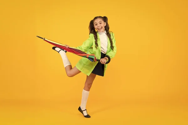 Voorspelling van toekomstige neerslag. Gelukkig kind naar school gaan in de nabije toekomst. Toekomstige school kind in regenjas met paraplu glimlachend op gele achtergrond. Toekomstige modetrends van het herfst seizoen — Stockfoto