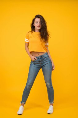 Seksi kız sarı arka plan. Seksi bir kız. Gündelik tarzda şehvetli bir kız. Güzellik ve makyaj. Uzun saçlı güzel bir kız. Moda ve tarz. Dar kot ona yakışıyor. Kendine güven en iyi ekiptir.