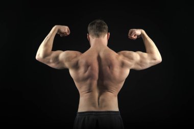 Siyah arka planda izole edilmiş pantolonla atletik vücut geliştirici pozu.