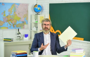 Sunum için tezin uygunluğundan emin olun. Evrak işleri belgesel dosyaları. Okul ödevi. Okula dönelim. Bilgi toplama günü. Erkek okul öğretmeni sınıfta oturur. Yakışıklı, olgun, akıllı eğitimci.