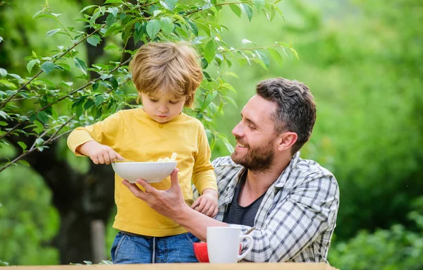 We are family. Morning breakfast. Vegetarian diet. family dinner time. happy fathers day. Little boy with dad eat cereal. healthy food and dieting. Dairy products. father and son eating outdoor — Stock Photo, Image