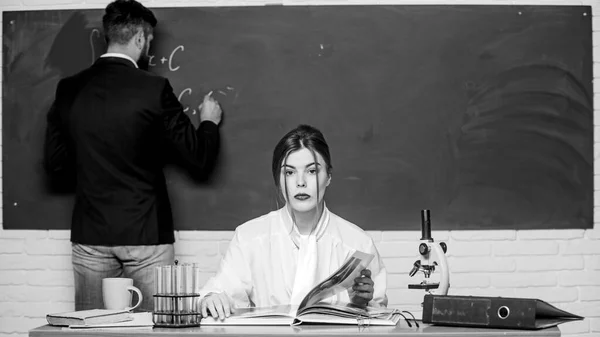 Running lesson in chemistry. Pretty chemistry teacher teach student in class. Bearded man answering chemistry at chalkboard in front of teacher. Education. School study — Stock Photo, Image