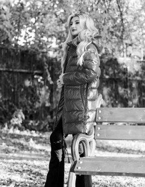 Sonbahar sezonu konsepti için ceket. Kız kırmızı parlak, kalın bir ceket giyiyor. Sonbahar moda konsepti. Kürsünün yanında ceketle poz veren çekici bir bayan. Sonbahar parkında makyajcı şık bir kadın.