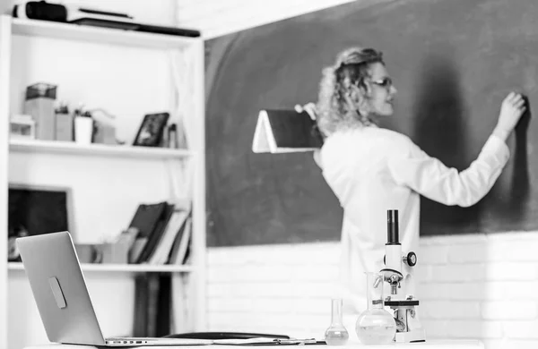 Studentka píše odpověď na tabuli. kádinka a mikroskop. student nepoužívá notebook. lekce biologie. Věda a biotechnologický výzkum. vzdělávání chemie. Zpátky do školy. selektivní zaměření — Stock fotografie