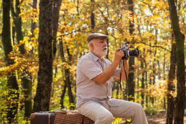 Her erkeğin bir hobisi vardır. Yaşlı adam sonbahar doğasında kameraya bakar. Hobi olarak fotoğrafçılık yapıyorum. Manzara ve doğa fotoğrafçılığı. Hobi ve yaşam tarzı. Hobisini çok seviyor.