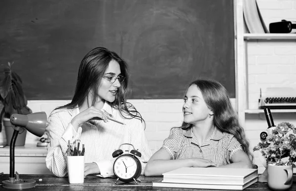 Homework project. Sister helping with learning. Teacher kind lady with pupil. Doing homework with mom. Little girl and woman sit at desk. School education. Studying together. Help with homework