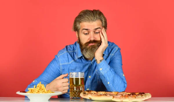 Bad appetite. Bored and sad. Beer and food. Dinner at pub. Hungry man going to eat pizza french fries and drink beer. Pizzeria restaurant. Upset man bearded hipster eat pizza. Pizza party concept
